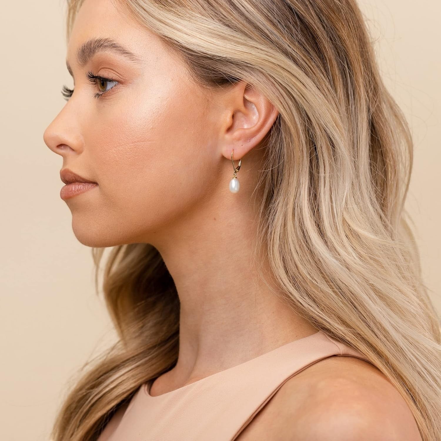 Prestige Pearl white freshwater pearl drop earrings with gold leverback settings worn by a woman in profile.
